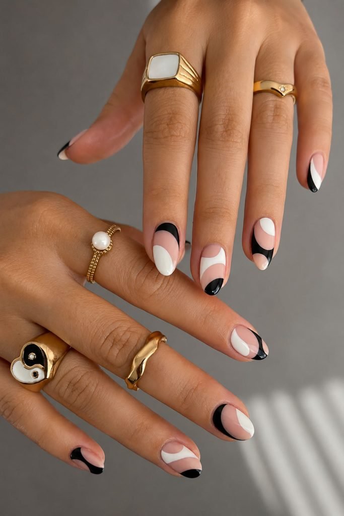 Abstract black and white nail designs featuring artistic swirl patterns on glossy almond nails