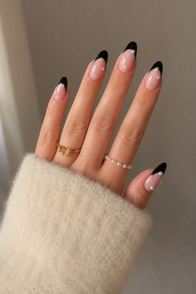 Black French tip nails with elegant pearl embellishments for a classy and sophisticated manicure