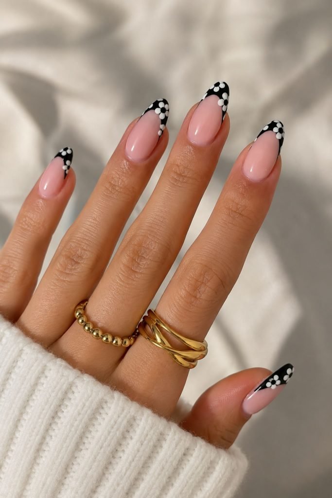 Black and white daisy manicure combining classic French tips with cute floral nail art