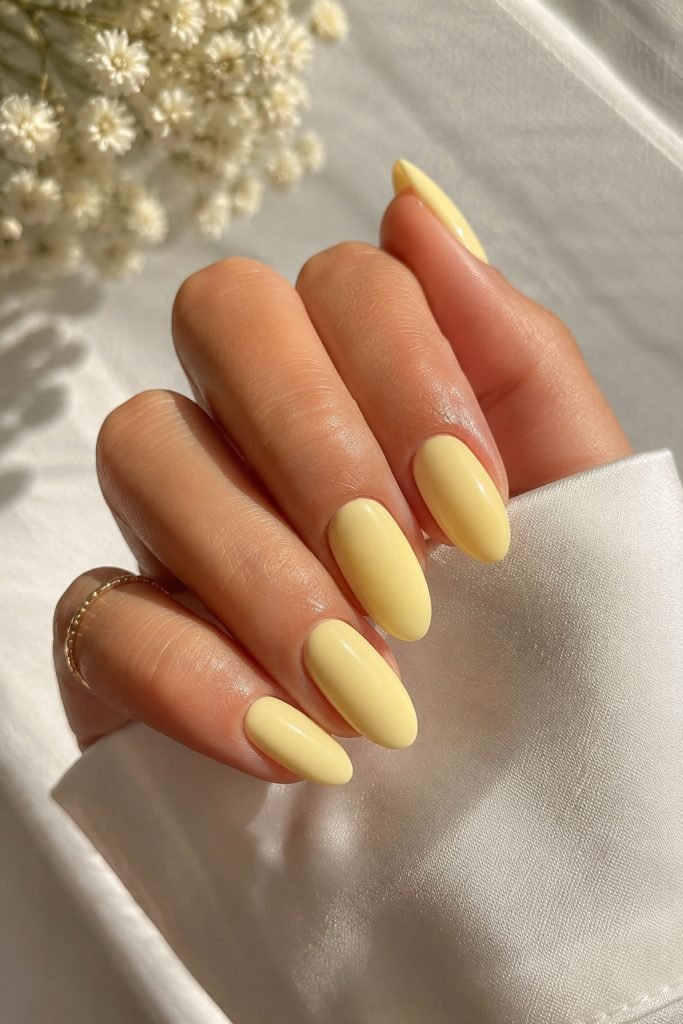 Butter yellow almond manicure with creamy pastel yellow glossy nails