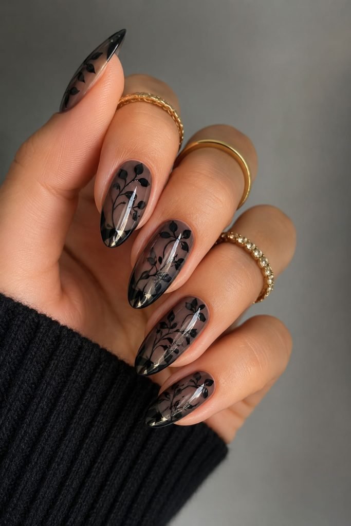 Classy botanical black nail designs featuring delicate floral artwork over sheer black polish