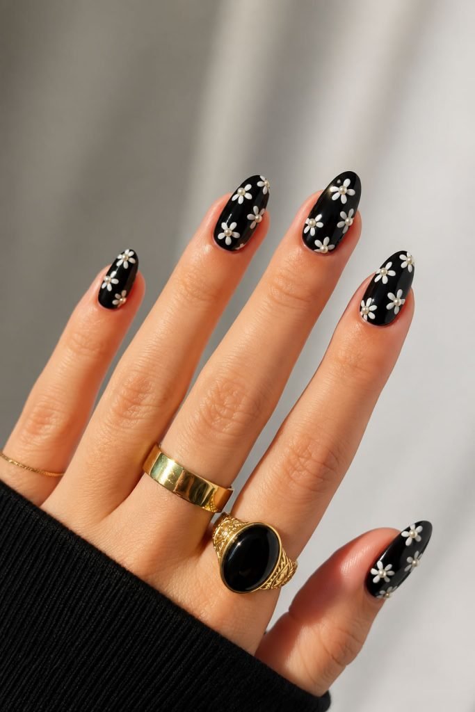 Cute black daisy nail art with pearl centers creating a playful and elegant floral manicure