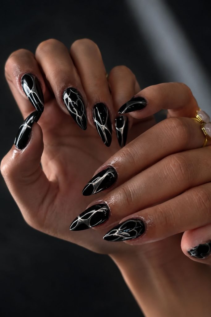 Edgy black nails with metallic silver accents inspired by futuristic chrome nail art trends