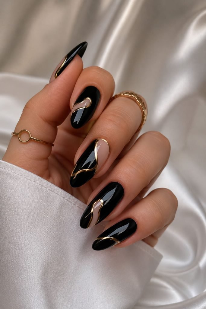 Glamorous black nails featuring metallic gold abstract nail art for an elegant luxury manicure