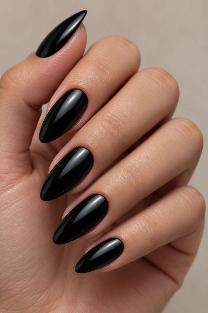 Glazed black manicure with glossy chrome finish on almond-shaped nails for a sleek and modern black nail design