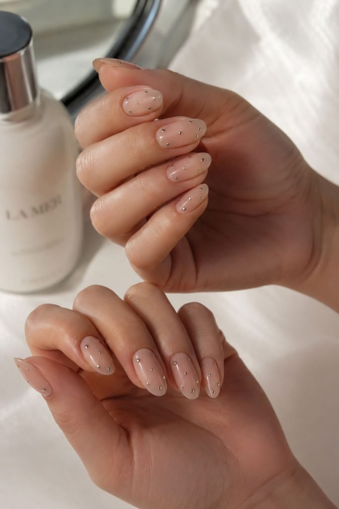 Simple dotted almond shaped nail designs with silver accents on nude almond nails