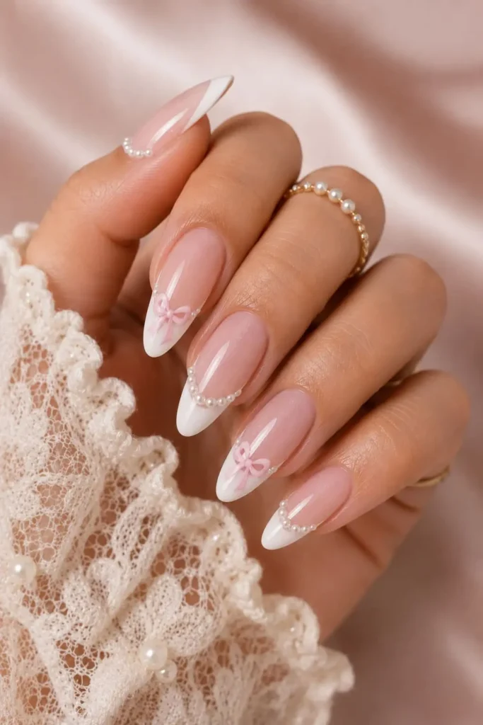 Coquette white French nails with pink bows and pearl accents