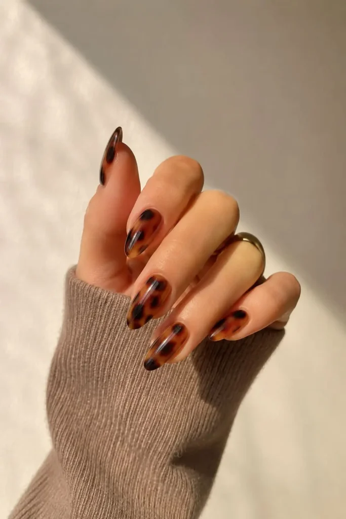 Glossy tortoiseshell gel nails with layered amber, caramel, and brown patterns