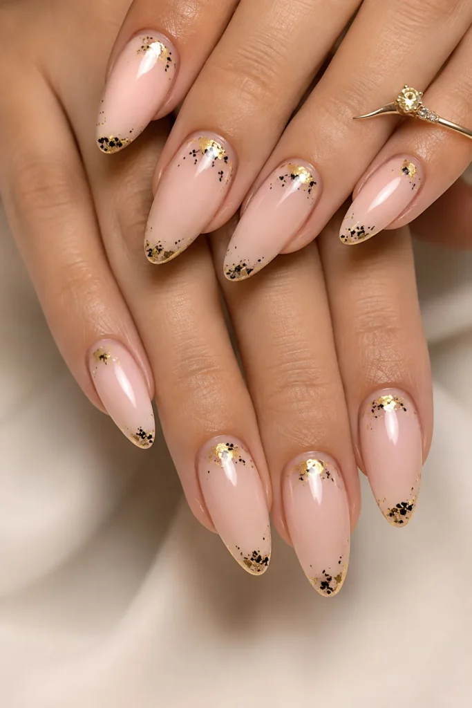 Elegant graduation nails with gold foil tips on a neutral almond base