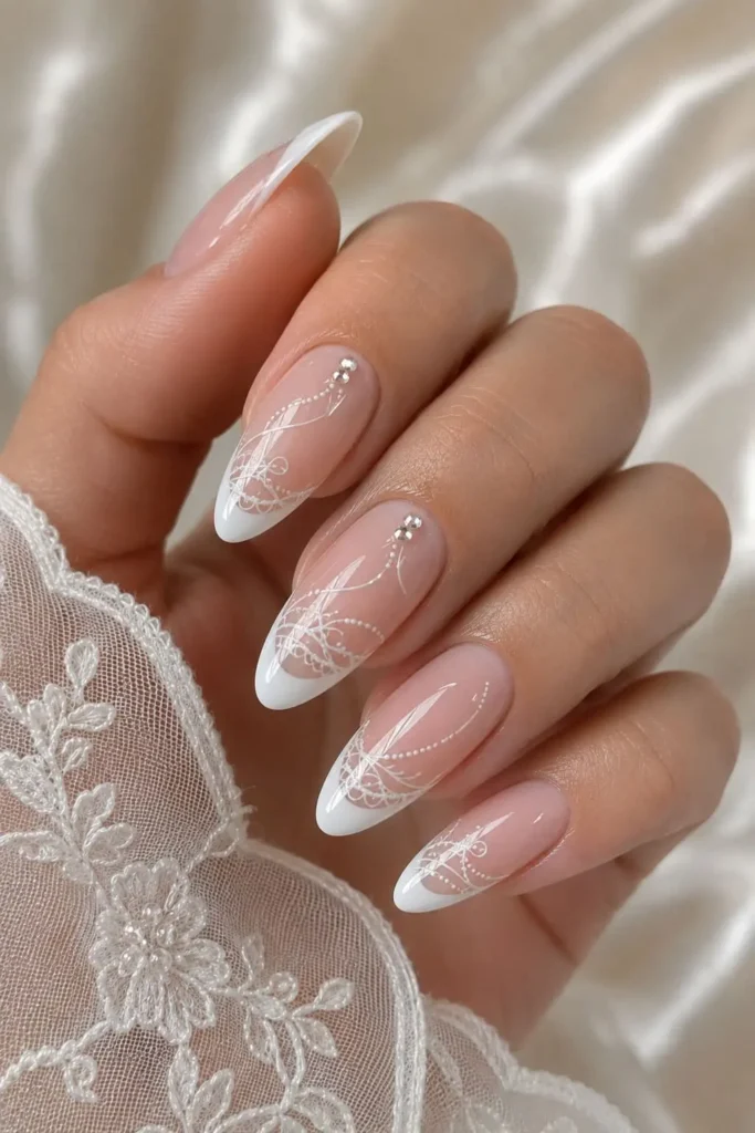 Lacy white French nails with delicate swirls and crystals