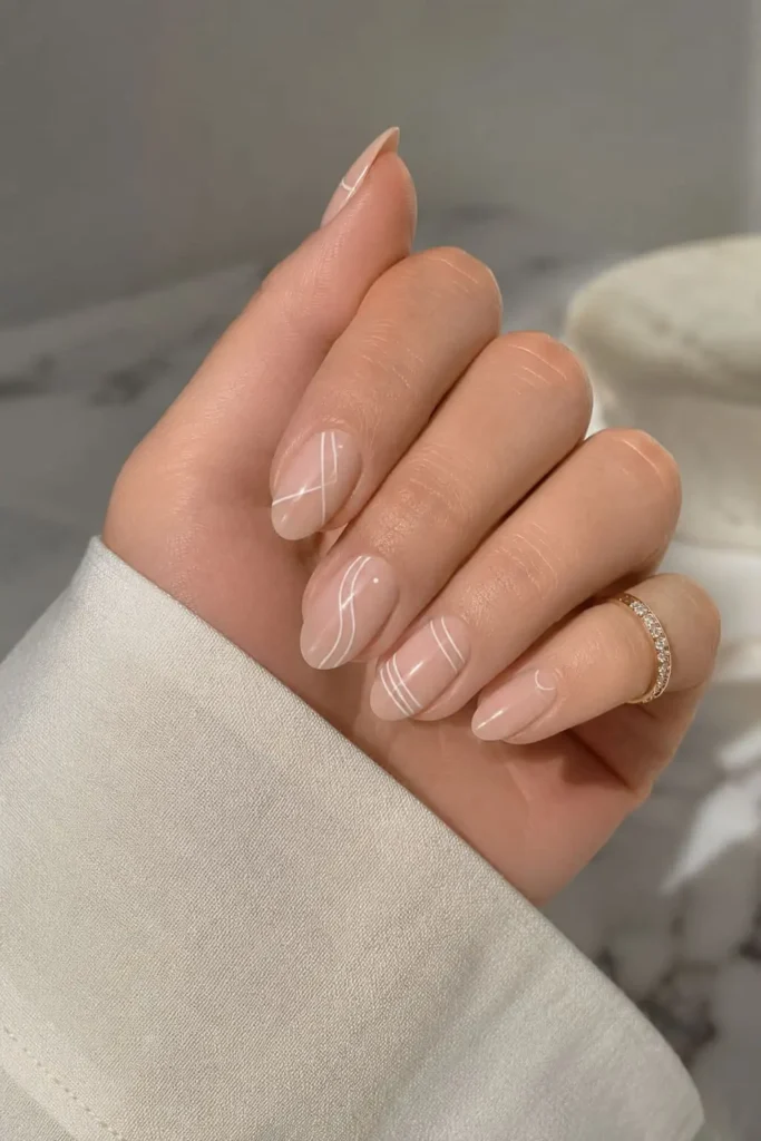 Minimalist nude nails with delicate white geometric linework and negative space