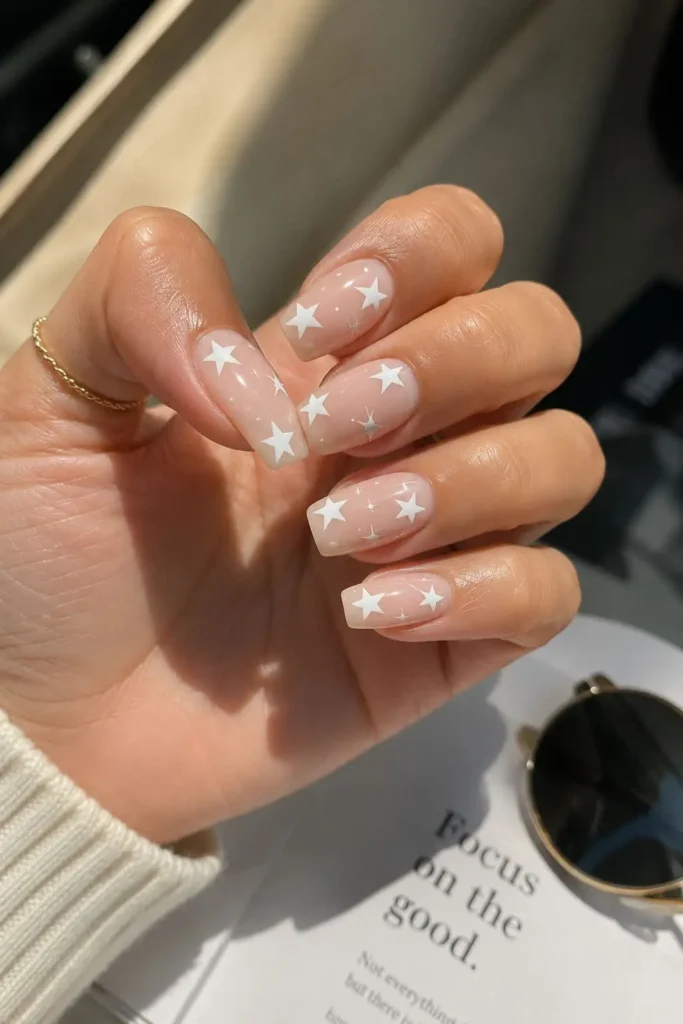 Nude star nail art with tiny celestial stars on a glossy neutral base