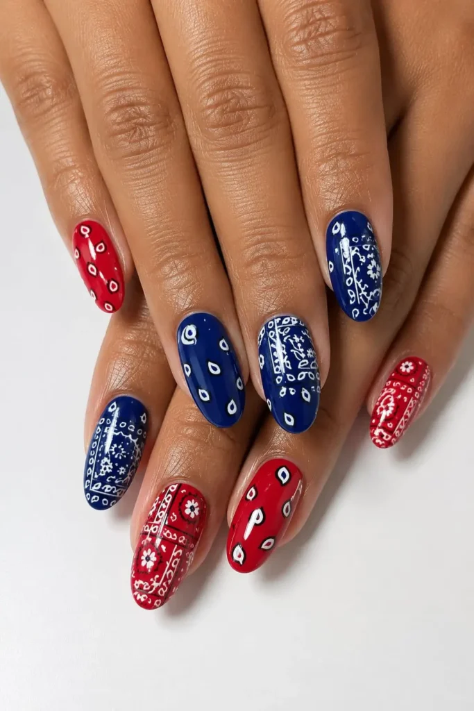 Red gel nails with intricate white paisley patterns and blue accents