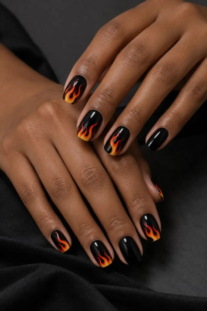 Black gel nails with bold orange flame tips