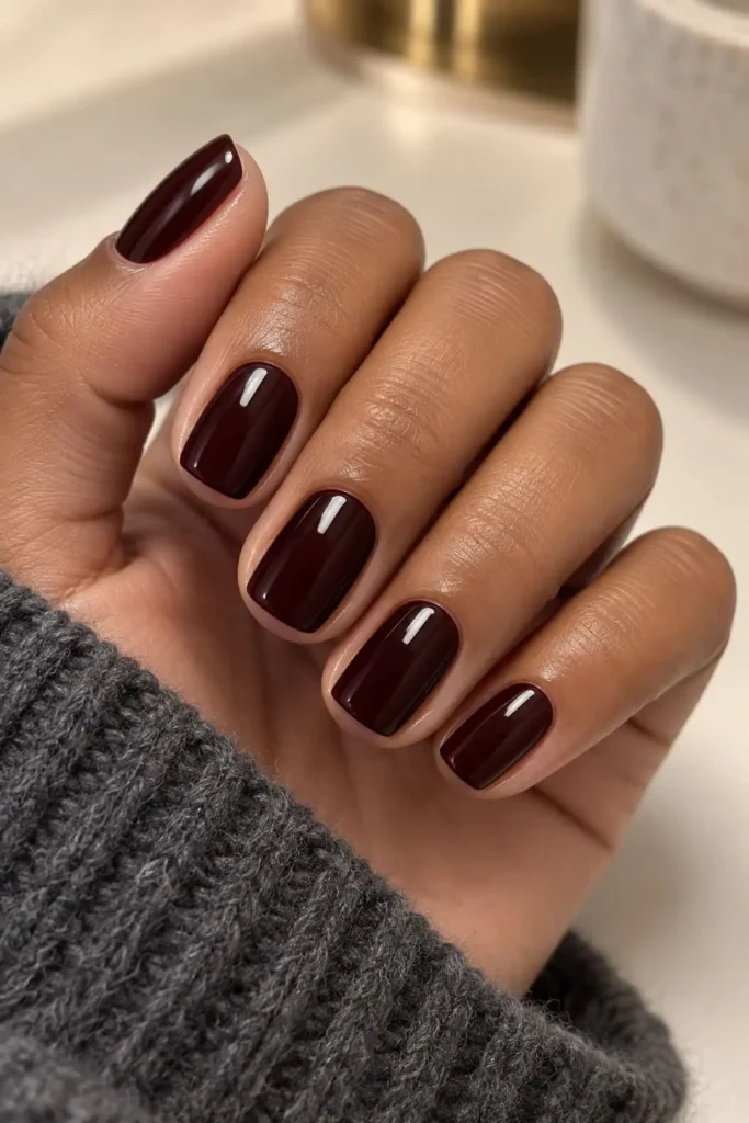 Glossy Bordeaux gel nails in a deep red-brown shade
