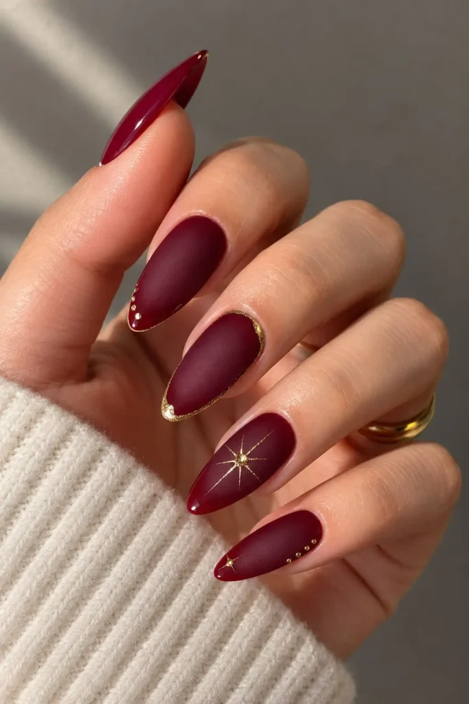 Burgundy and gold aura nails with metallic accents and delicate star details