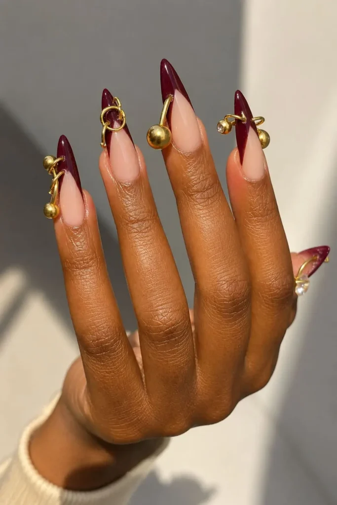 Burgundy nails with gold metallic accents and elegant 3D nail details