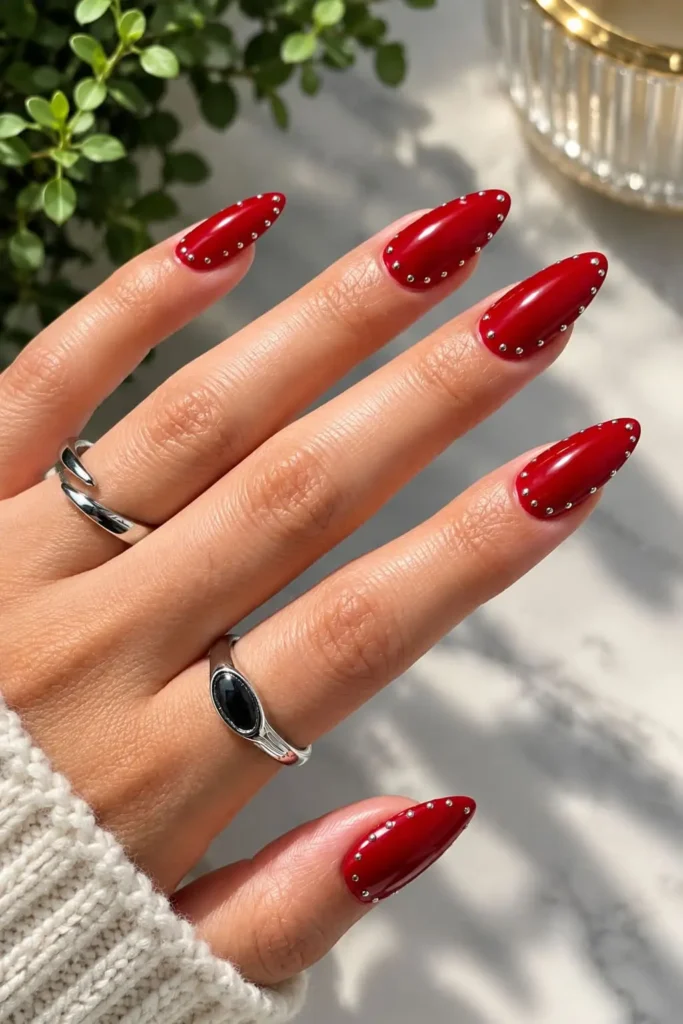 Red gel nails with silver chrome stud frames around the edges