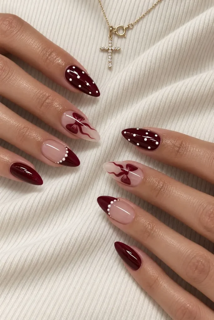Deep maroon nails with a cute bow accent and elegant dark red finish