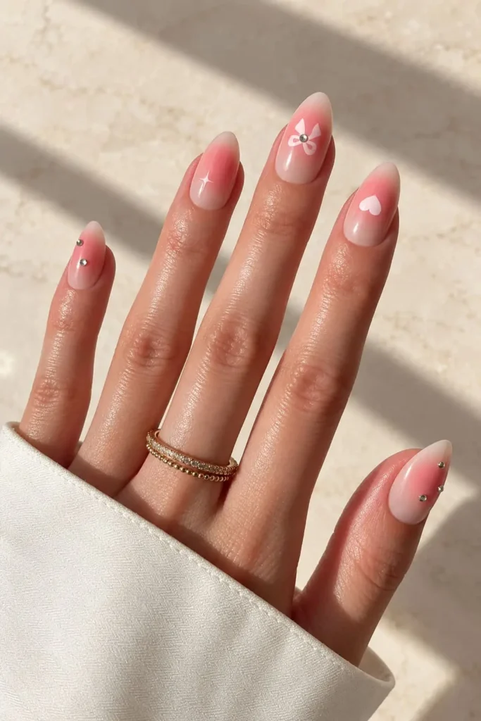 Pink coquette bow nails with hearts, gemstones, and feminine accents