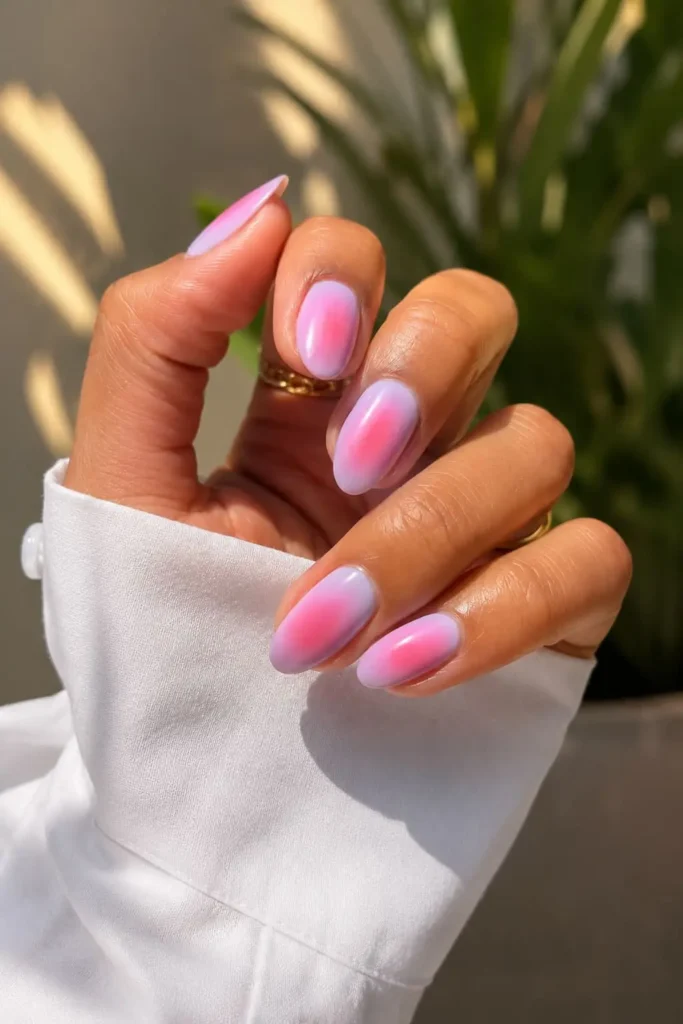 Short acrylic aura nails with a soft glowing pink and purple halo effect