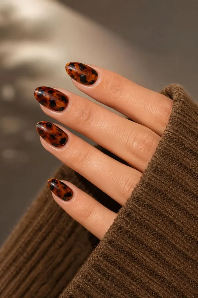 Short acrylic tortoiseshell nails with translucent amber, brown, and black veining