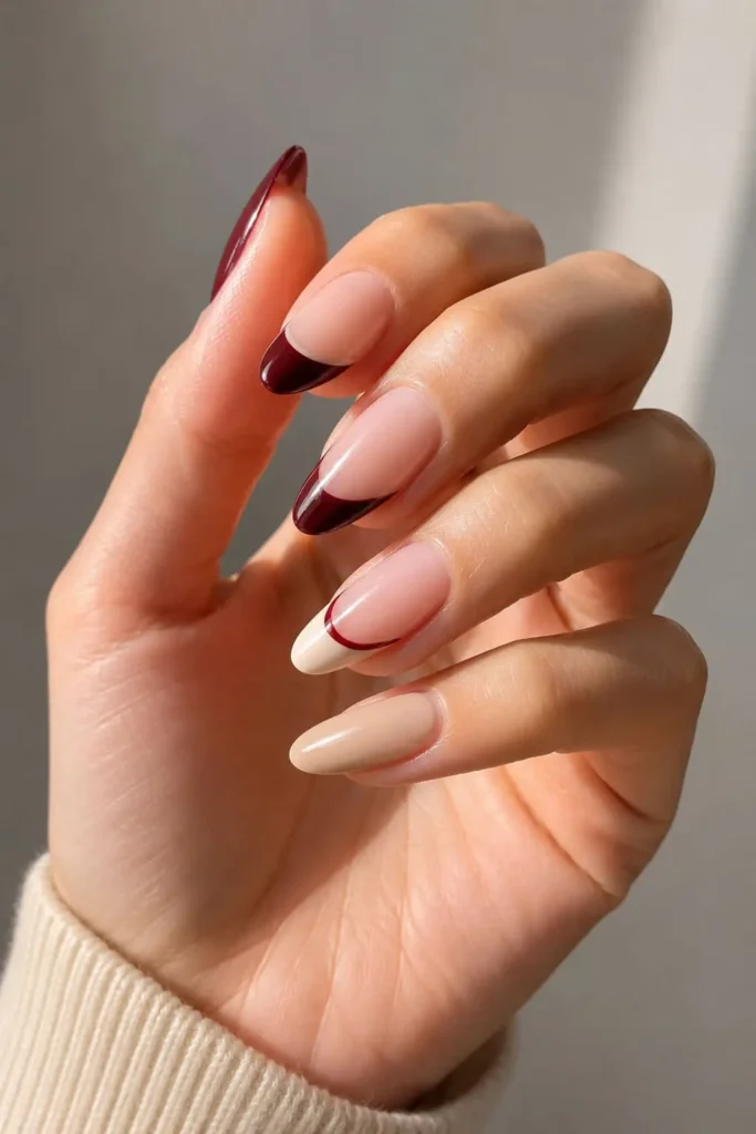Two-tone burgundy French tips with navy accents on short nails